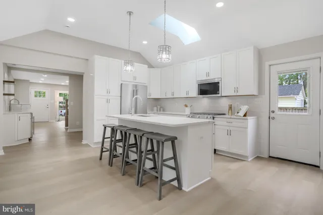 a kitchen that has a lot of white cabinets and stainless steel appliances