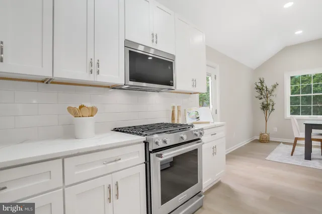 a kitchen with stainless steel appliances granite countertop a stove a microwave and white cabinets