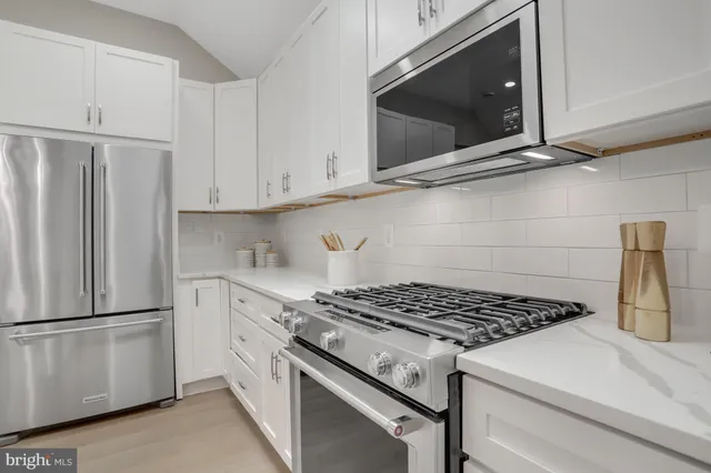 a kitchen with white cabinets and appliances