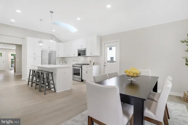 a kitchen with kitchen island a dining table chairs stainless steel appliances and cabinets