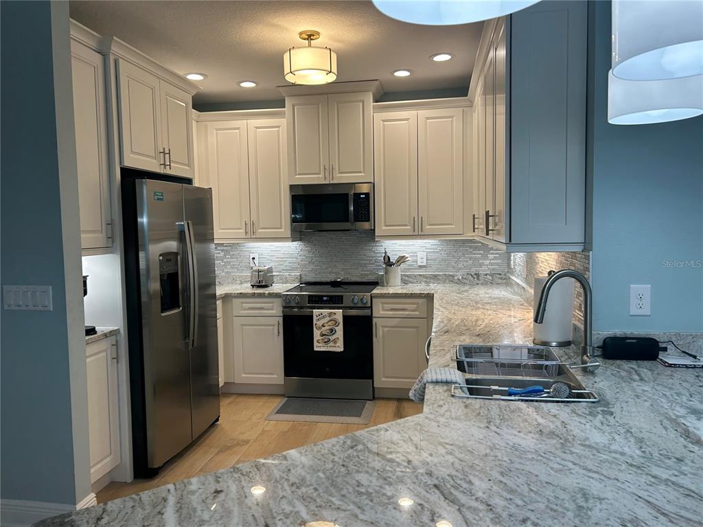 3426 79th Street Circle West, Unit 203 Bradenton, FL 34209 - Photo 5 of 30 a kitchen with stainless steel appliances granite countertop a refrigerator a stove a sink and a microwave