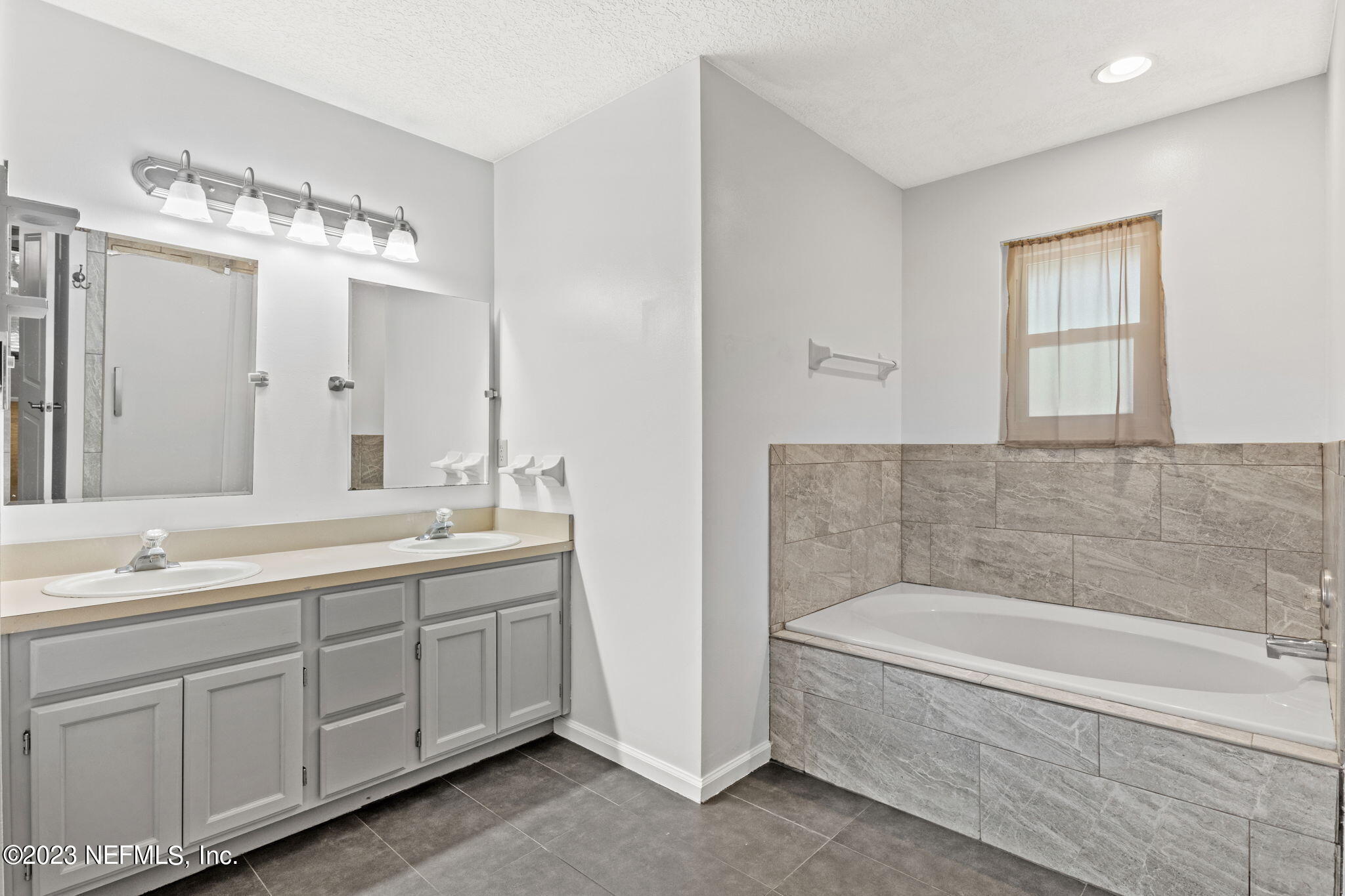 3233 Fritz Road Jacksonville, FL 32226 - Photo 25 of 43 a bathroom with a tub a double vanity sink and a mirror