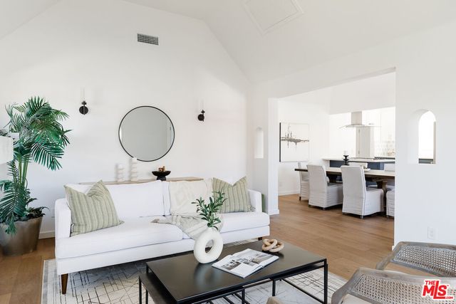 a living room with furniture kitchen view and a potted plant