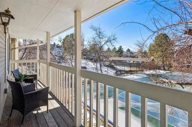 a view of a balcony with chairs and wooden fence