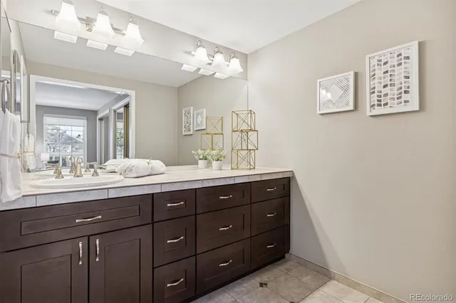 a bathroom with a granite countertop double vanity sink and a mirror