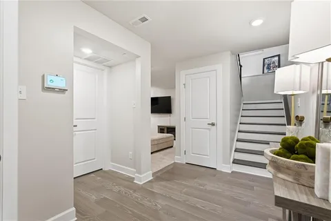 a view of a hallway to room with wooden floor and entryway