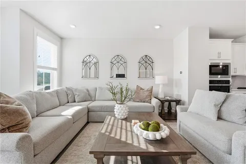 a living room with furniture kitchen view and a window