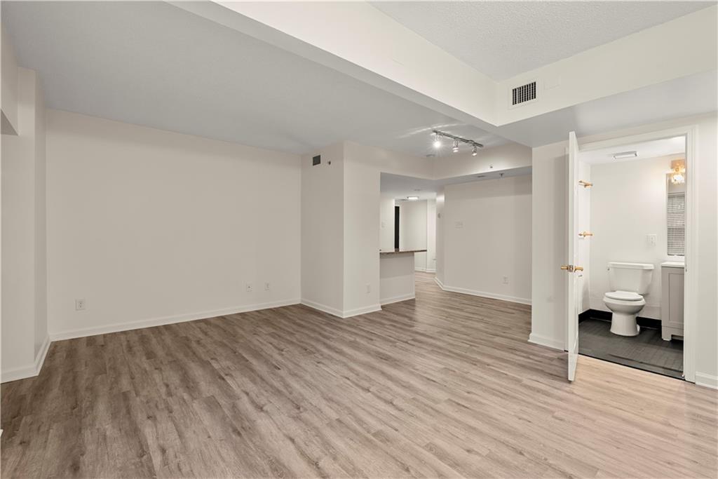 199 14th Street Northeast, Unit 201 Atlanta, GA 30309 - Photo 7 of 42 a view of an empty room and a hallway with wooden floor and a bathroom