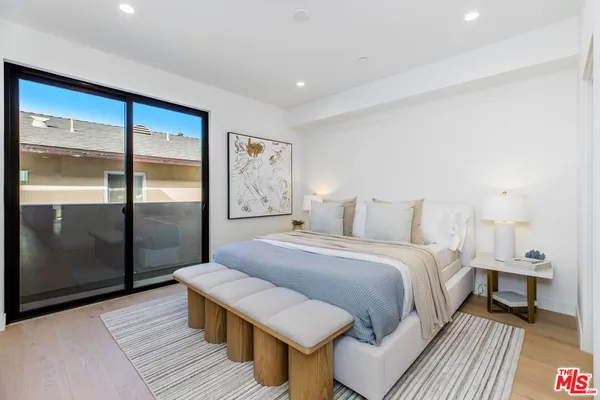 a spacious bedroom with a bed and wooden floor