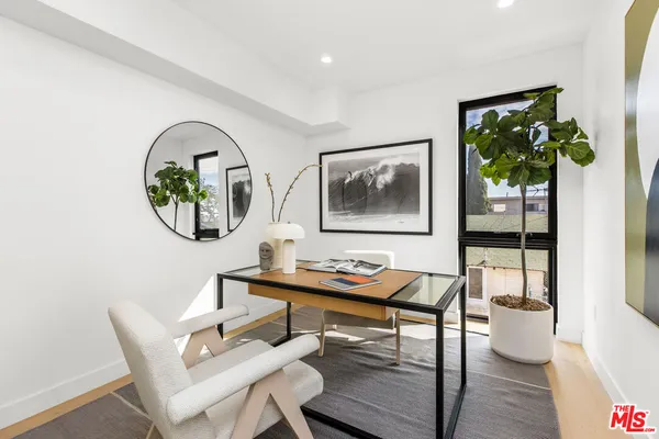 a view of a dining room with furniture a potted plant and wooden floor