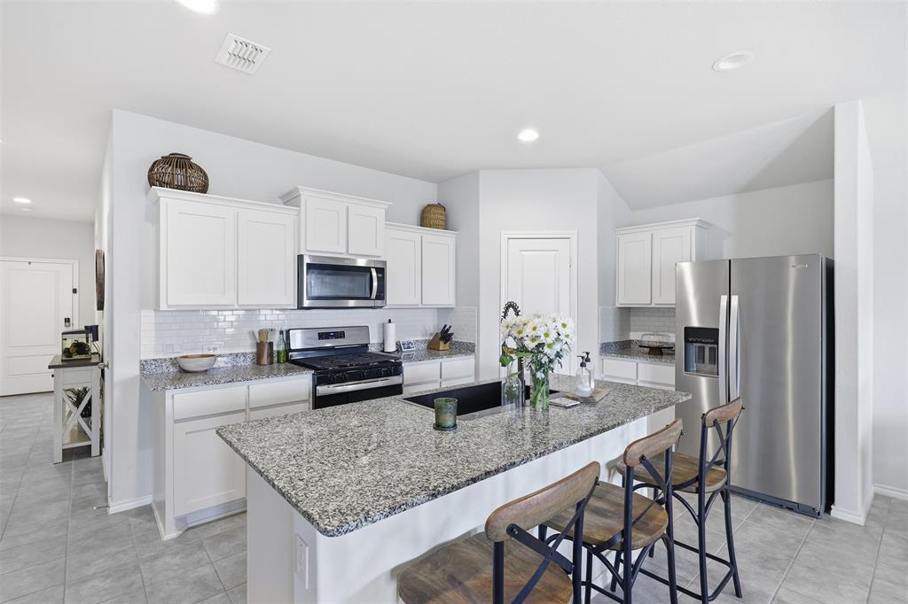 613 Whitecomb Lane Justin, TX 76247 - Photo 4 of 39 a kitchen with stainless steel appliances granite countertop a refrigerator and a stove top oven