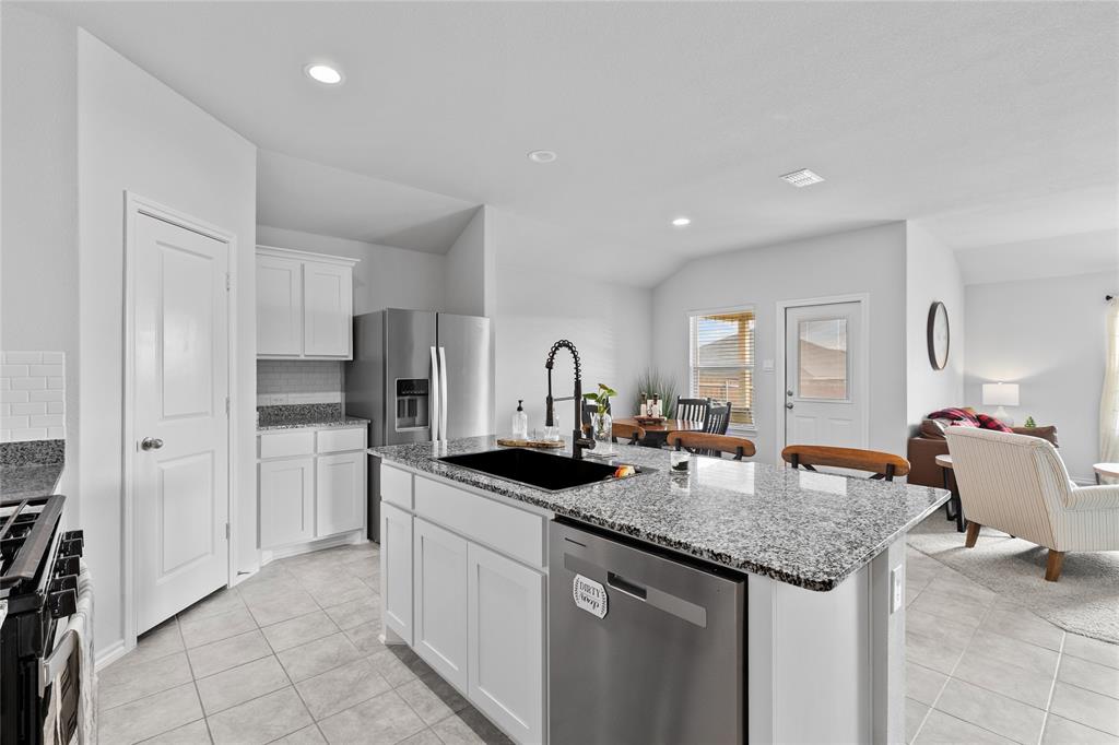 613 Whitecomb Lane Justin, TX 76247 - Photo 7 of 29 a kitchen with granite countertop kitchen island sink refrigerator and cabinets