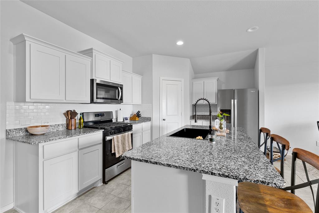 613 Whitecomb Lane Justin, TX 76247 - Photo 8 of 29 a kitchen with granite countertop a sink a stove and cabinets