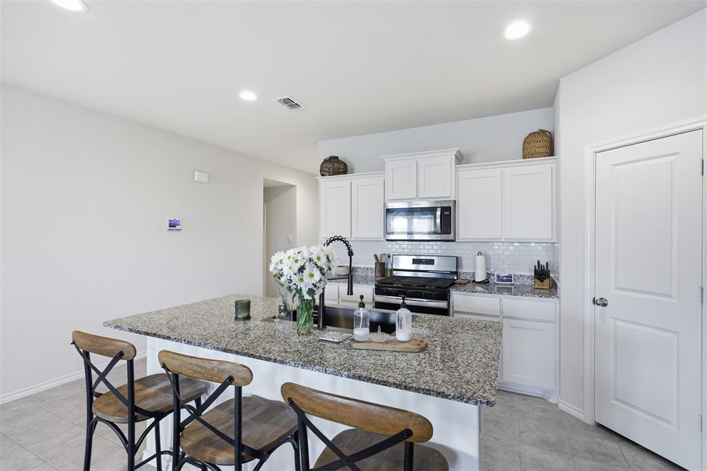 613 Whitecomb Lane Justin, TX 76247 - Photo 9 of 39 a kitchen with stainless steel appliances granite countertop a dining table chairs and refrigerator