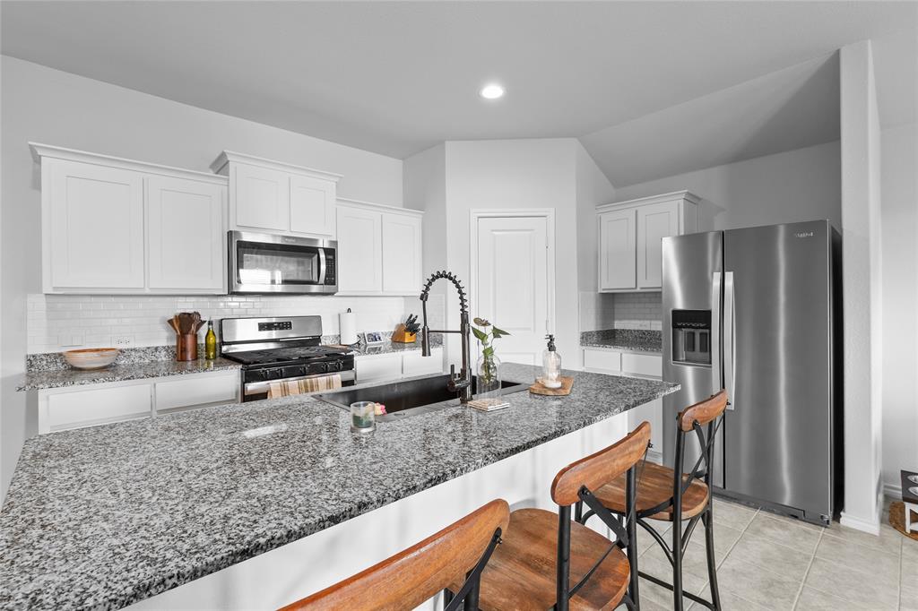 613 Whitecomb Lane Justin, TX 76247 - Photo 9 of 29 a kitchen with stainless steel appliances granite countertop a table chairs sink refrigerator and microwave