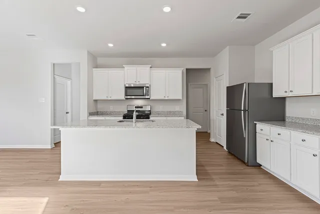 a view of kitchen with granite countertop stainless steel appliances refrigerator oven stove microwave and cabinets