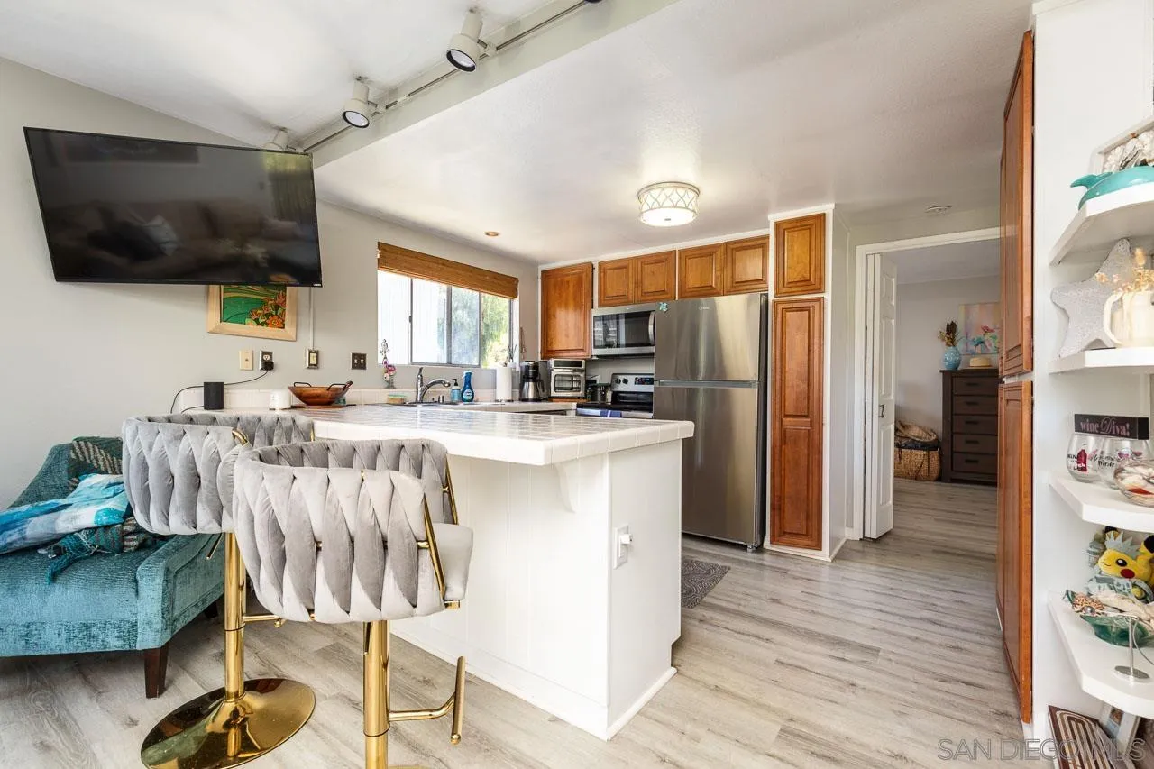 155 Rosebay Drive, Unit 28 Encinitas, CA 92024 - Photo 7 of 23 a kitchen with stainless steel appliances kitchen island granite countertop a refrigerator a stove top oven a dining table and chairs with wooden floor