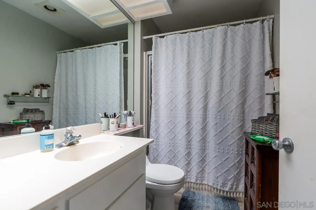 155 Rosebay Drive, Unit 28 Encinitas, CA 92024 - Photo 10 of 23 a bathroom with a sink a toilet and shower curtain