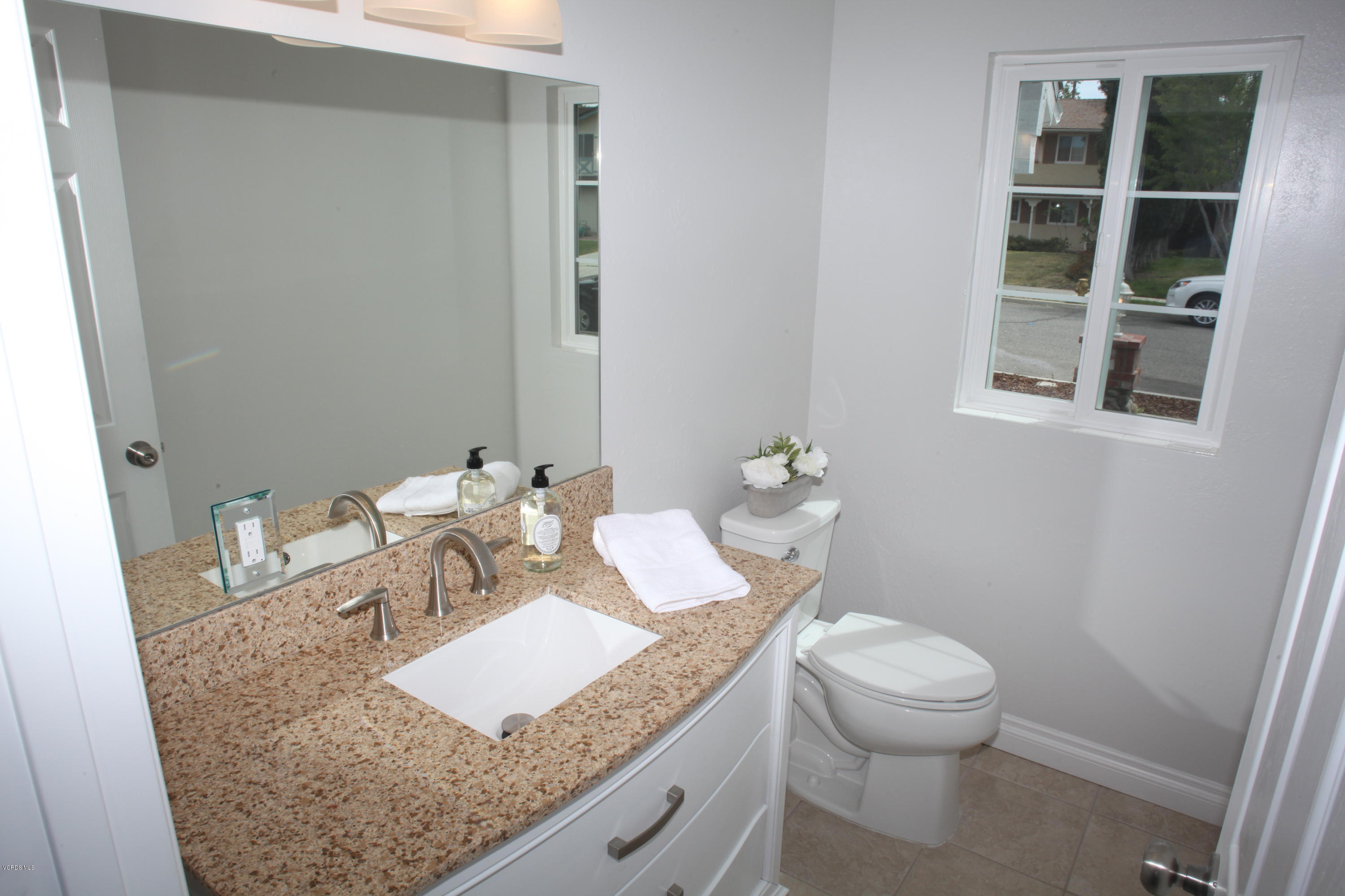 2061 Rhoda Street Simi Valley, CA 93065 - Photo 8 of 27 a bathroom with a granite countertop sink a toilet and a mirror