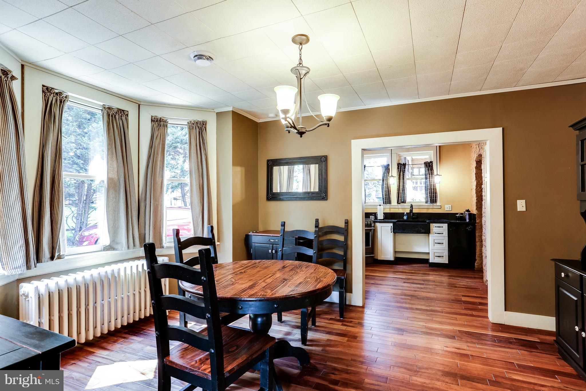 100 Hillside Road Baltimore, MD 21228 - Photo 10 of 30 a dining room with wooden floor a chandelier a wooden table and chairs