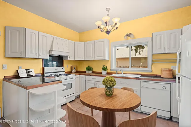 a kitchen with a sink cabinets a stove a kitchen island and chairs