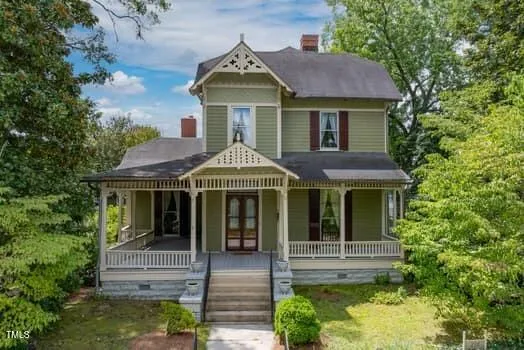 a view of a white house with large windows and a small yard