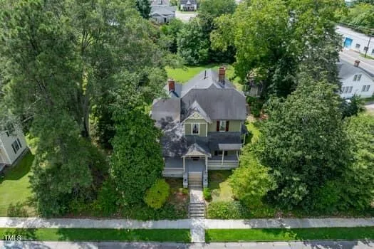 an aerial view of a house with a yard and large trees
