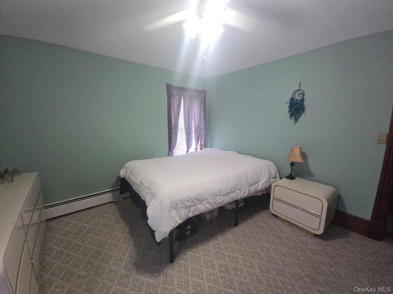 59 Bridge Street, Unit 2 Wallkill, NY 12589 - Photo 11 of 14 Carpeted bedroom with ceiling fan and a baseboard heating unit