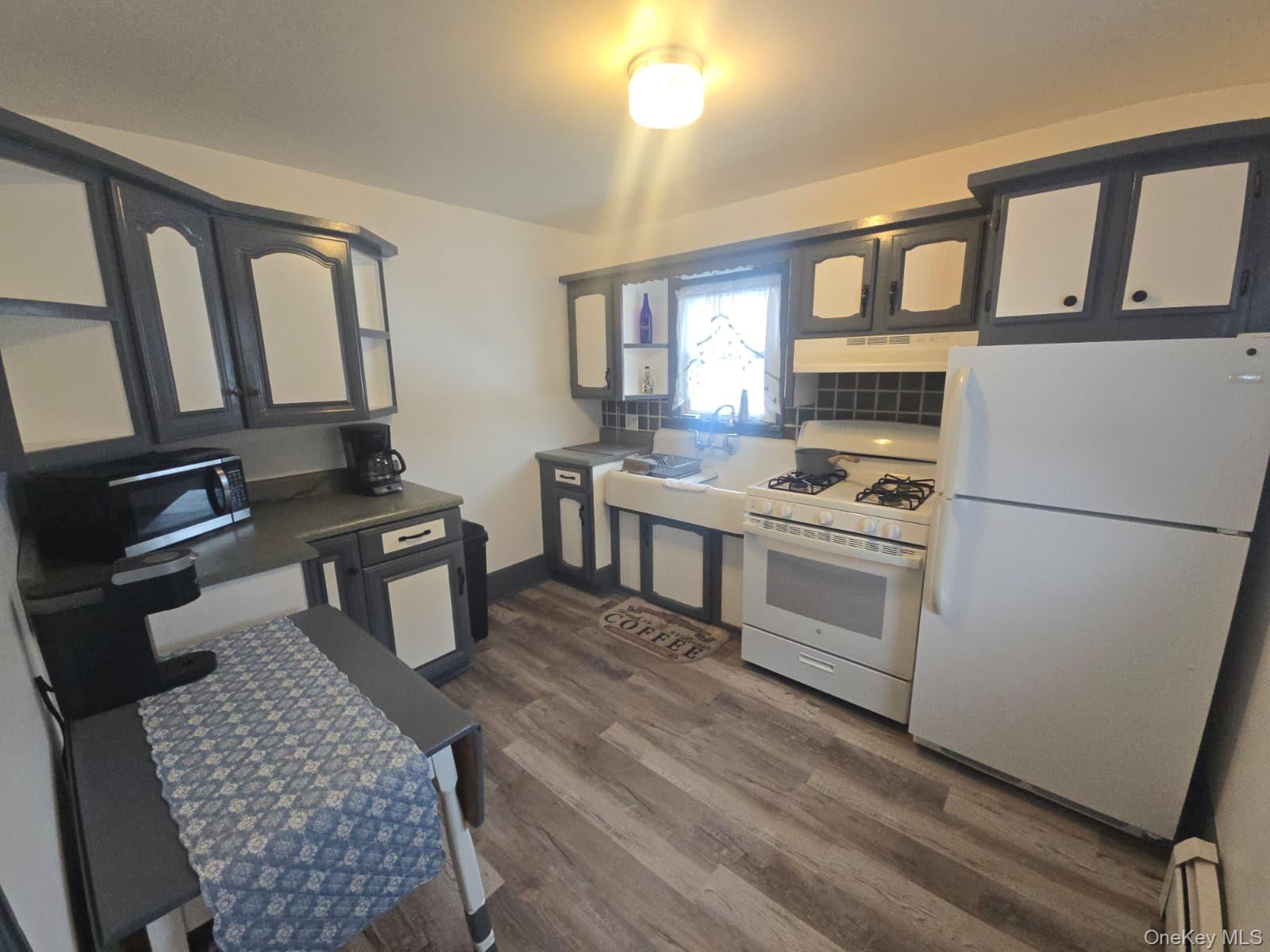 59 Bridge Street, Unit 2 Wallkill, NY 12589 - Photo 2 of 14 Kitchen with white appliances, dark countertops, dark wood-style flooring, under cabinet range hood, and a baseboard heating unit