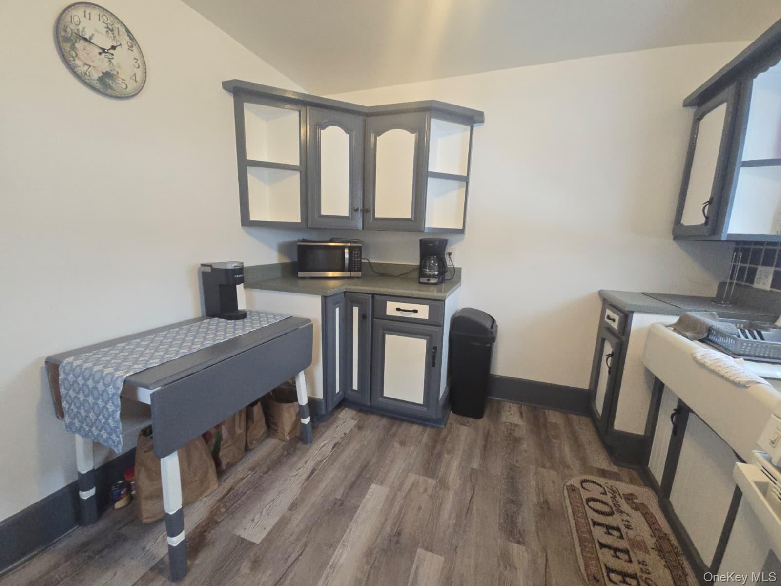 59 Bridge Street, Unit 2 Wallkill, NY 12589 - Photo 4 of 14 Kitchen with dark countertops, dark wood-type flooring, gray cabinets, open shelves, and stainless steel microwave