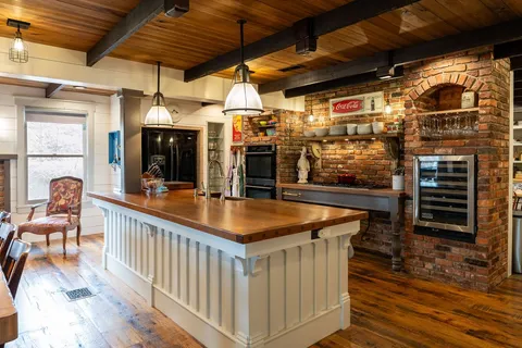 a dining hall with stainless steel appliances kitchen island granite countertop a table chairs and a barbeque view