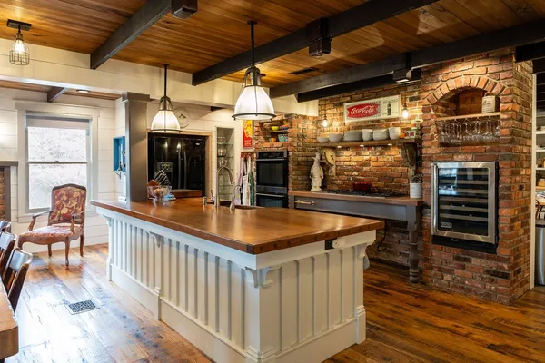 a dining hall with stainless steel appliances kitchen island granite countertop a table chairs and a barbeque view