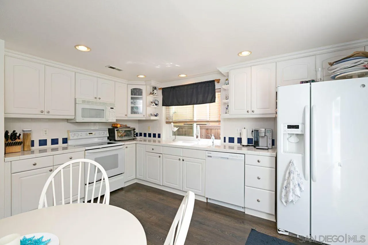 946 Alyssum Road Carlsbad, CA 92011 - Photo 8 of 19 a kitchen with white cabinets and stainless steel appliances