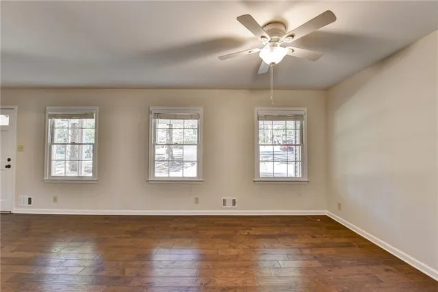 an empty room with wooden floor and windows