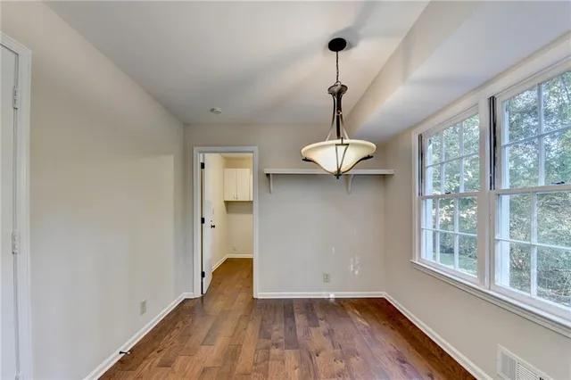 an empty room with a chandelier fan and windows
