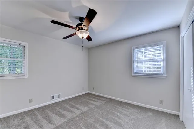 a view of a refrigerator in kitchen and an empty room with wooden floor