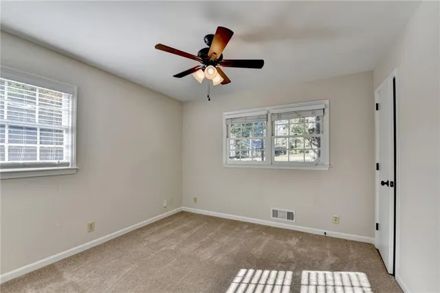 an empty room with wooden floor ceiling fan and windows