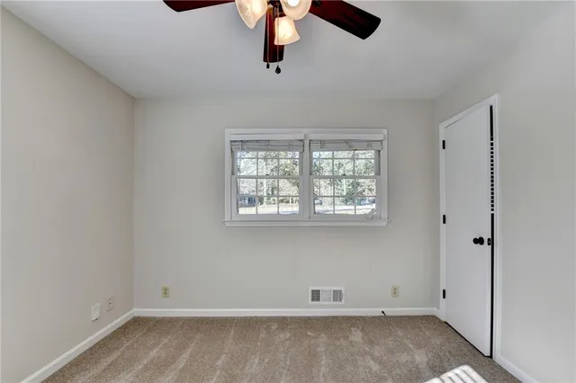 an empty room with wooden floor and ceiling fan