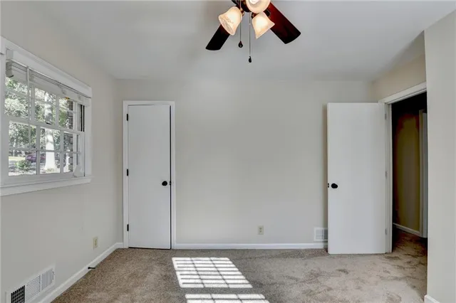 a view of empty room with wooden floor and ceiling fan