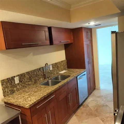 a kitchen with granite countertop a sink and a refrigerator