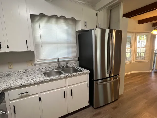 a kitchen with stainless steel appliances granite countertop a refrigerator a sink and white cabinets