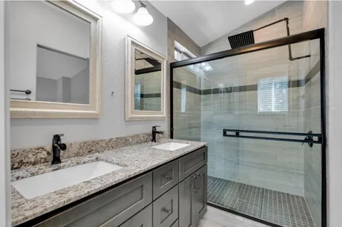 a bathroom with a granite countertop sink mirror and a shower