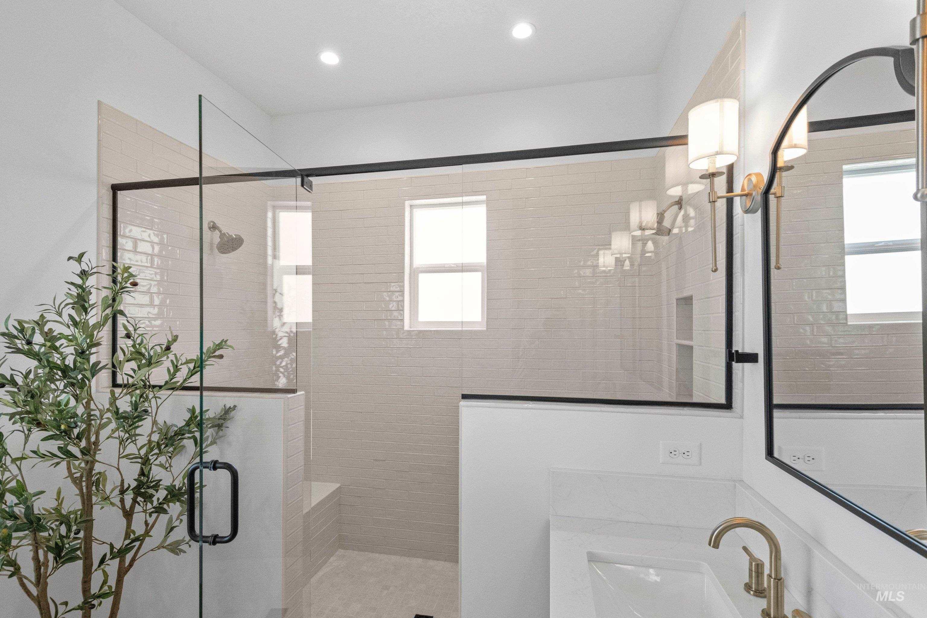 24990 Belgian Way Middleton, ID 83644 - Photo 26 of 50 Walk-in shower with clear glass enclosure and black trim, featuring a built-in bench and white subway tile surround