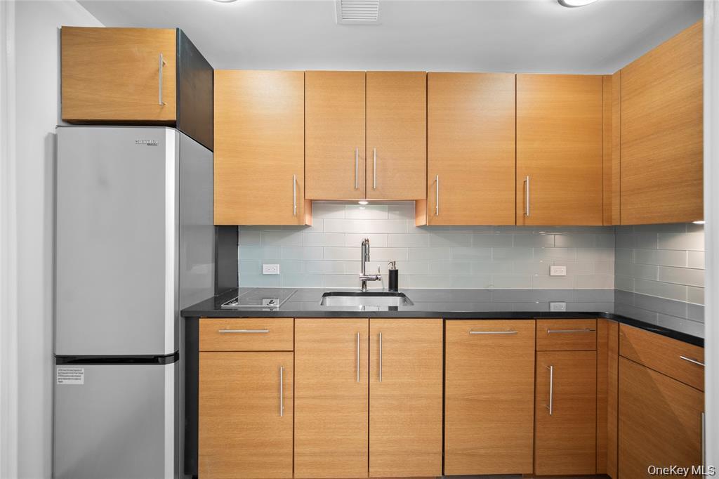 1 Renaissance Square, Unit 10A White Plains, NY 10601 - Photo 9 of 27 a kitchen with stainless steel appliances granite countertop a sink a refrigerator and a cabinets