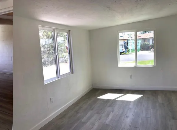 an empty room with wooden floor and windows