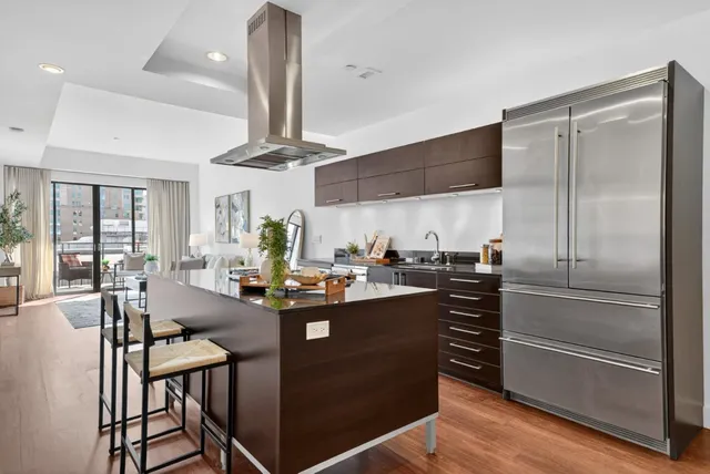a kitchen with stainless steel appliances a dining table chairs stove and refrigerator