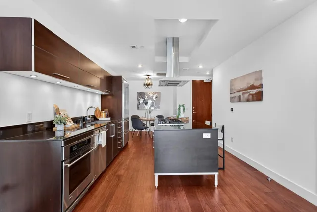 a kitchen with stainless steel appliances a stove a sink dishwasher and a refrigerator with wooden floor