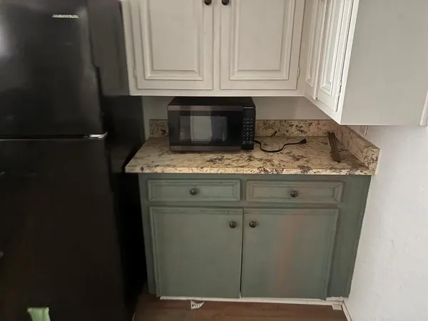 a kitchen with granite countertop white cabinets and sink