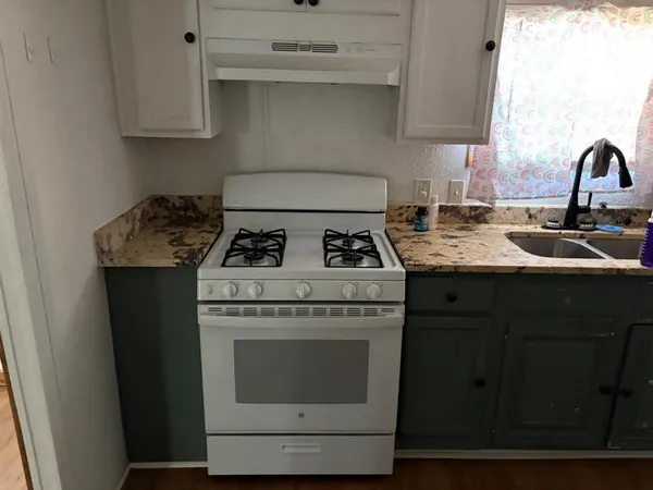 a kitchen with granite countertop a stove sink and cabinets