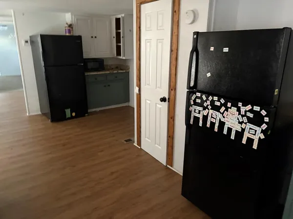 a view of a kitchen with refrigerator and wooden floor